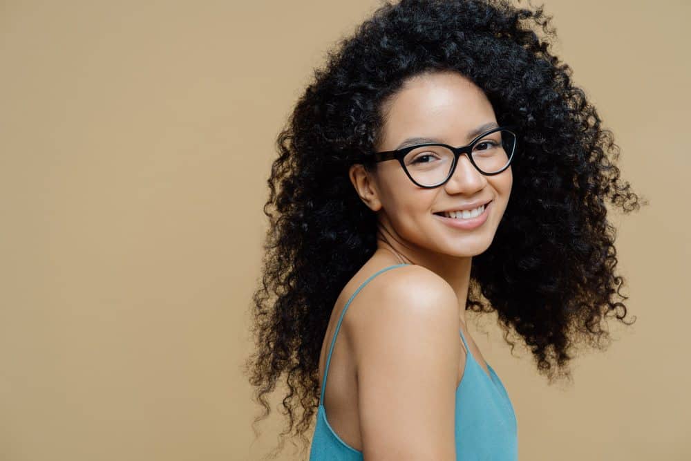 African American woman with naturally curly hair ready to learn how to use bergamot essential oil for her hair growth needs.