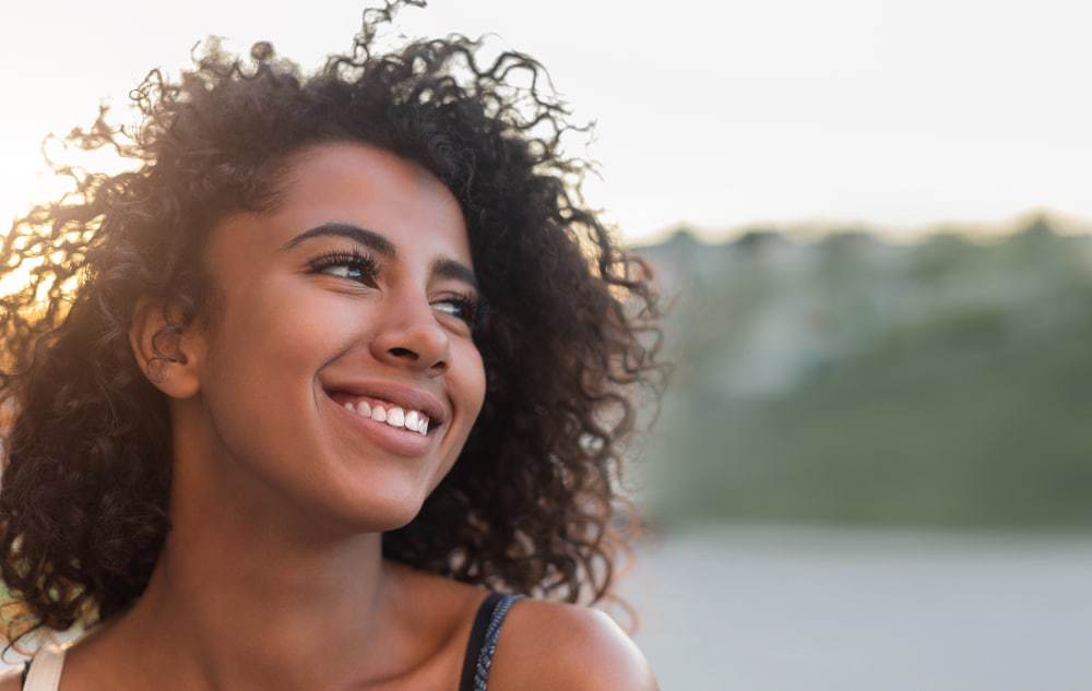 Outdoor portrait of beautiful smiling African American woman wearing a sundress.