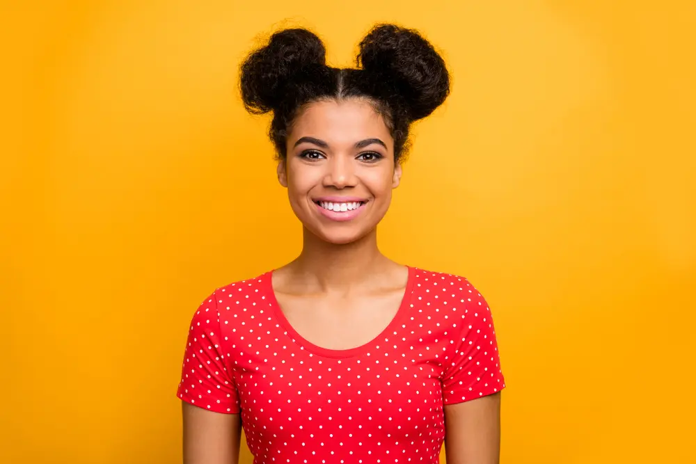 How to Do Space Buns: Easy, Step-by-Step Tutorial for Beginners 1 Portrait of candid pretty nice girl enjoy spring free time holiday look, smiling in camera wear bright clothes isolated over vivid color background