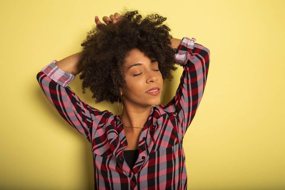 Young African woman isolated on yellow wall studio teen style shouting close-up.