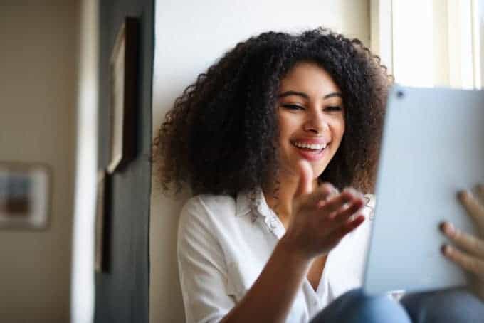 Lady leaning on the wall while reading Curl Centric's website on her iPad