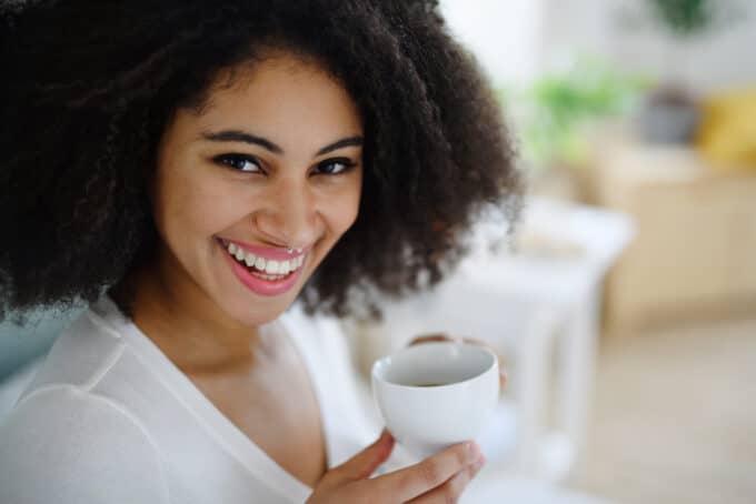 Cute girl wearing a white shirt while drinking coffee during breakfast