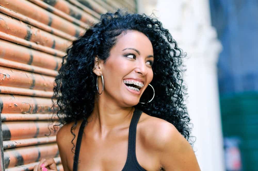 Young black woman smiling with braces and naturally curly hair.