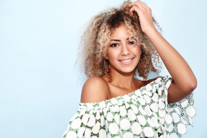 Cute black girl with naturally curly hair wearing a green and white shirt.