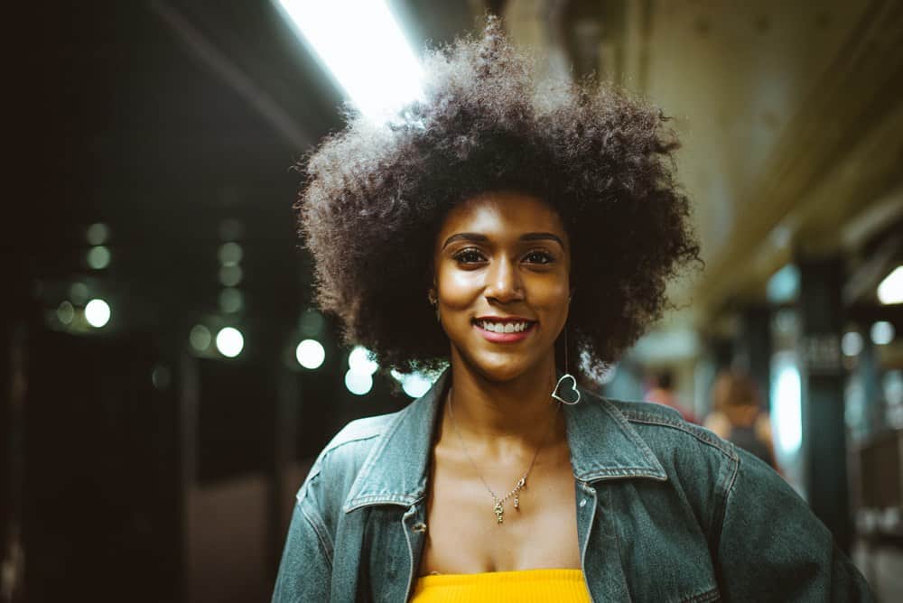 Lady showing her onion juice for hair growth after photo on her naturally curly type 4C hair.