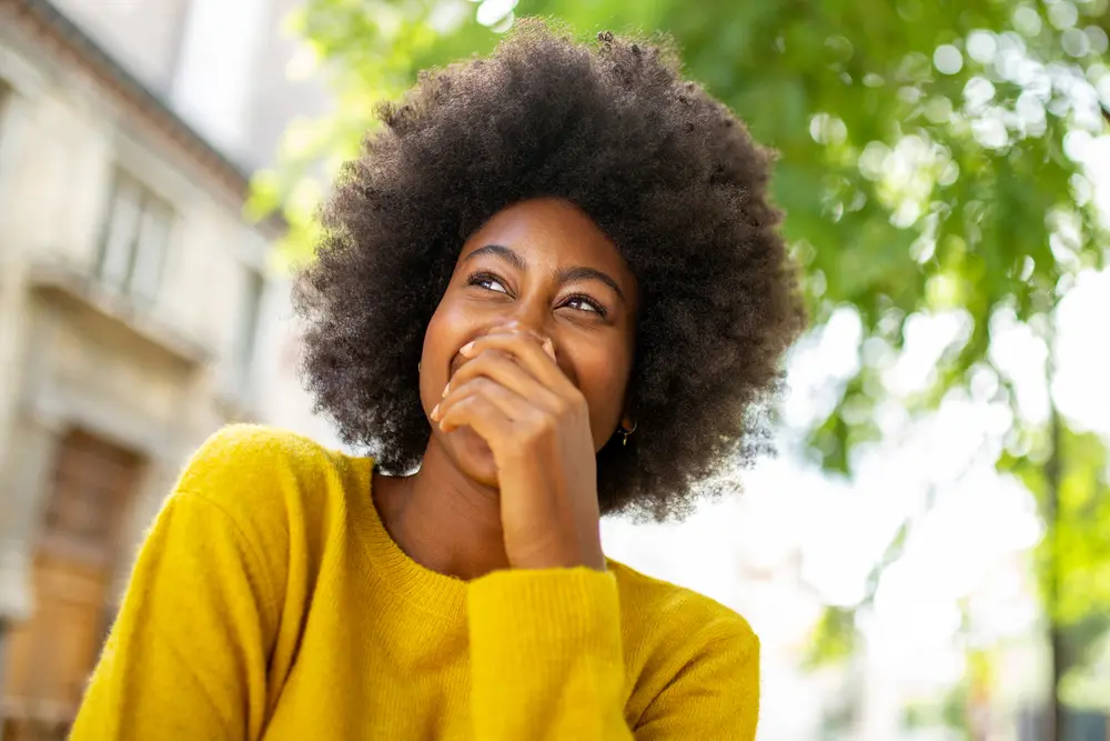 Black girl wearing a sweater with type 4D naturally curly hair.