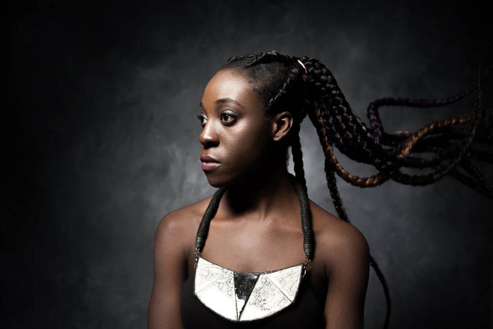 Black female looking into the distance, wearing a black dress.