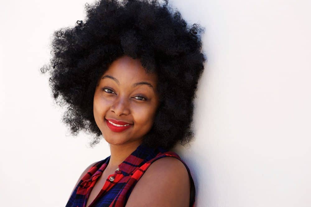 Pretty African American woman with 4C hair type wearing a red and blue flannel shirt.