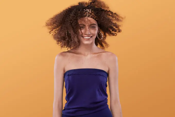 Beautiful young mixed-race female wearing a blue dress with bouncy curls styled with texturizing spray