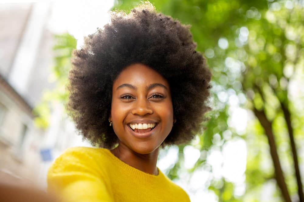 African American women wearing a yellow sweater with gold earrings. 