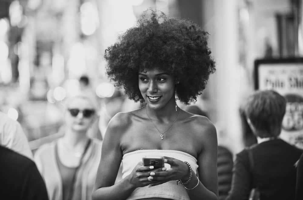 African American women with 4D hair styled with an essential oil standing in a crowd wearing a crop top.