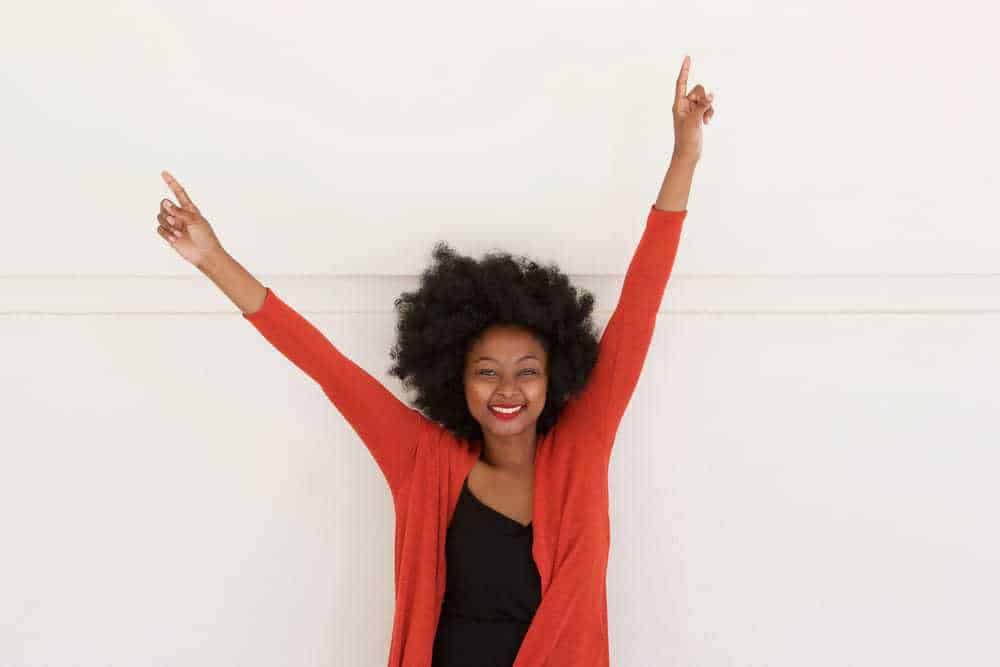 Black girl wearing a red sweater with a curly wash n go styled with organic products