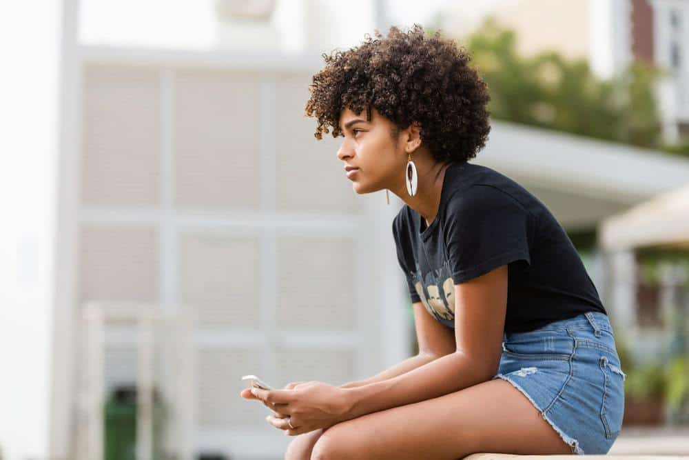 Cute black girl wearing a t-shirt and blue jeans with afro earrings.