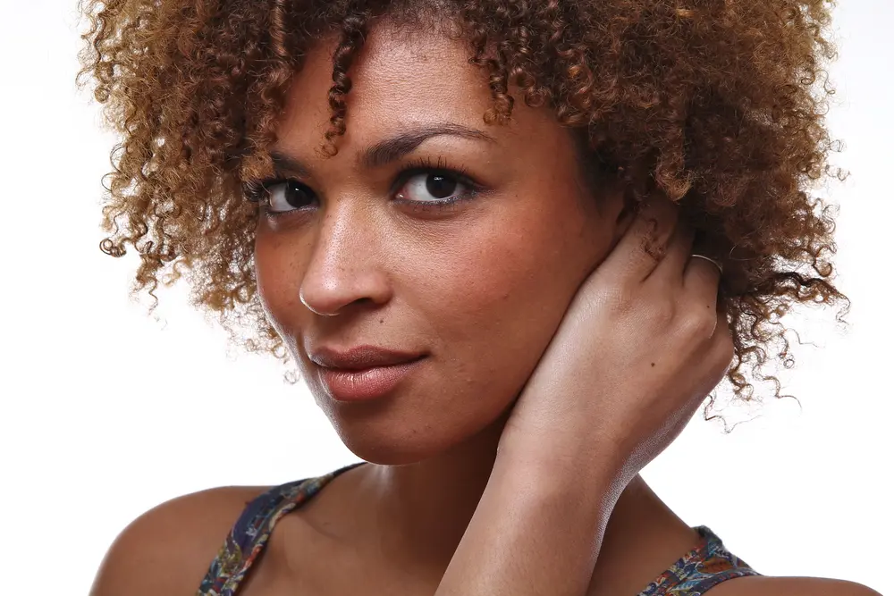 Beautiful African American female with naturally curly hair looking directly into the camera. 