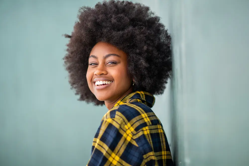How To Grow Natural Hair Faster: Grow Hair Fast Step-by-Step 2 Pretty African American female wearing a yellow and blue plaid shirt, earrings, with long 4C natural hair.