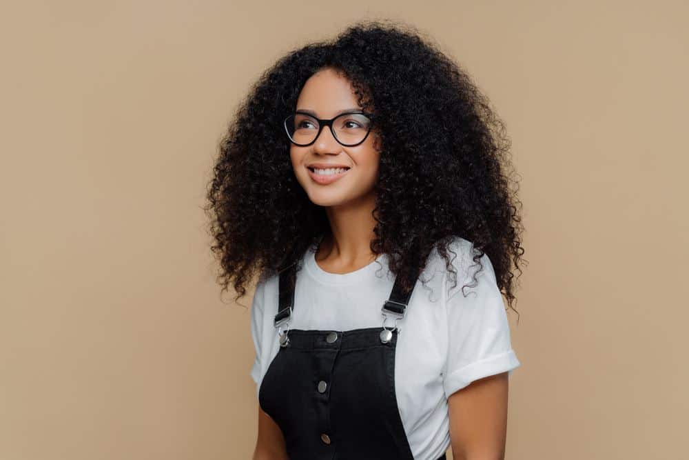 Cute American woman wearing black Tommy Hilfiger overalls and a white Hanes t-shirt with natural hair.