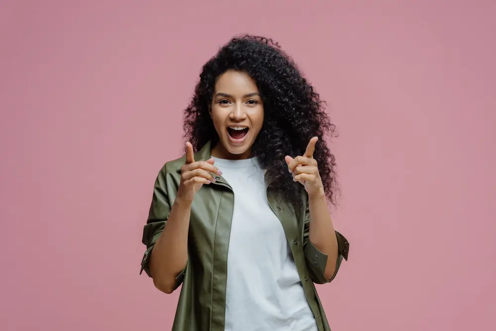 Bergamot Oil: How to Use Bergamot Oil for Hair Growth & More 9 Happy black women pointing towards the camera wearing a green shirt and white t-shirt.