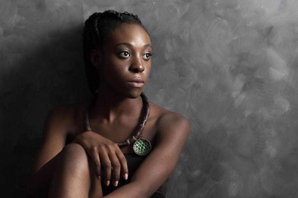 Black women in deep thought looking into the distance wearing a necklace.