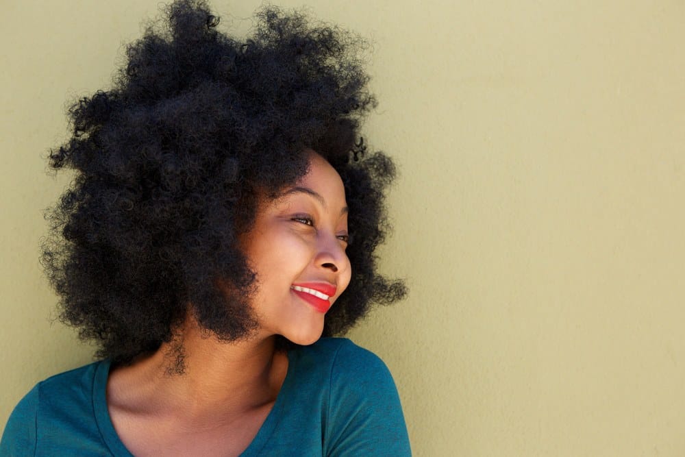 Black lady with curly hair extensions mixed with her own hair creating a big curly afro