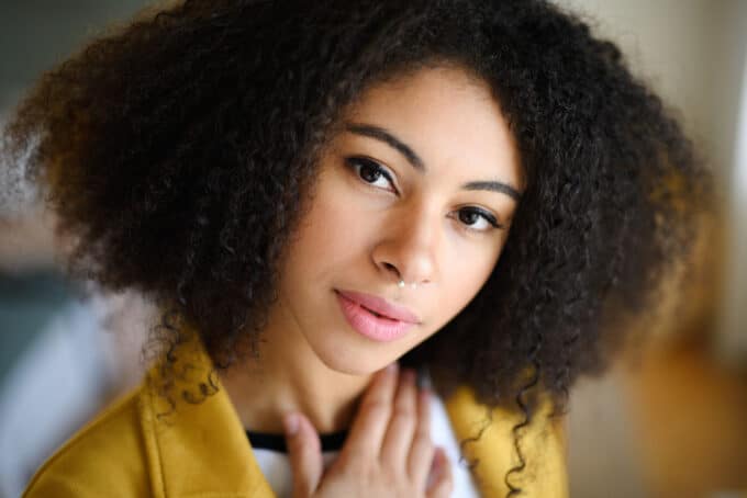 African American women with 4a curls wearing a white t-shirt and a yellow jacket