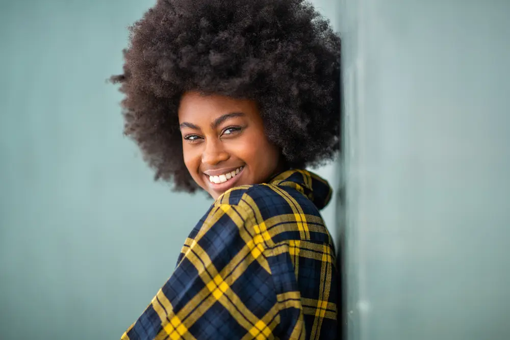 Cute black woman smiling with beautiful type 4D naturally curly hair.