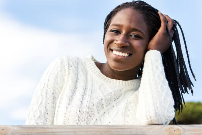 African American female wearing a white sweater with 4C hair.