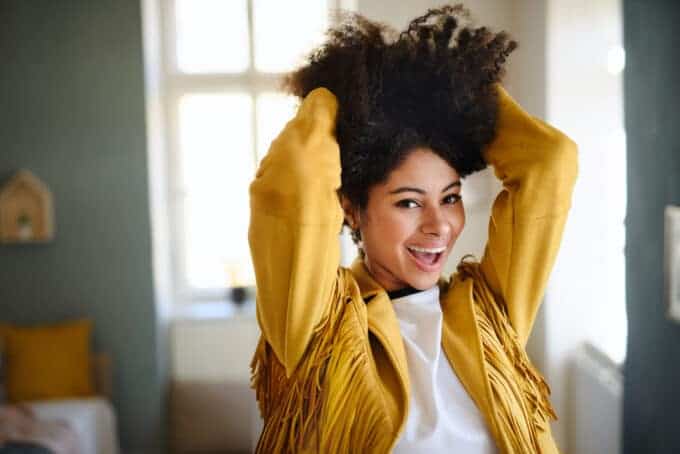 Adult female with a yellow cowgirl jacket rubbing her fingers through her naturally curly hair