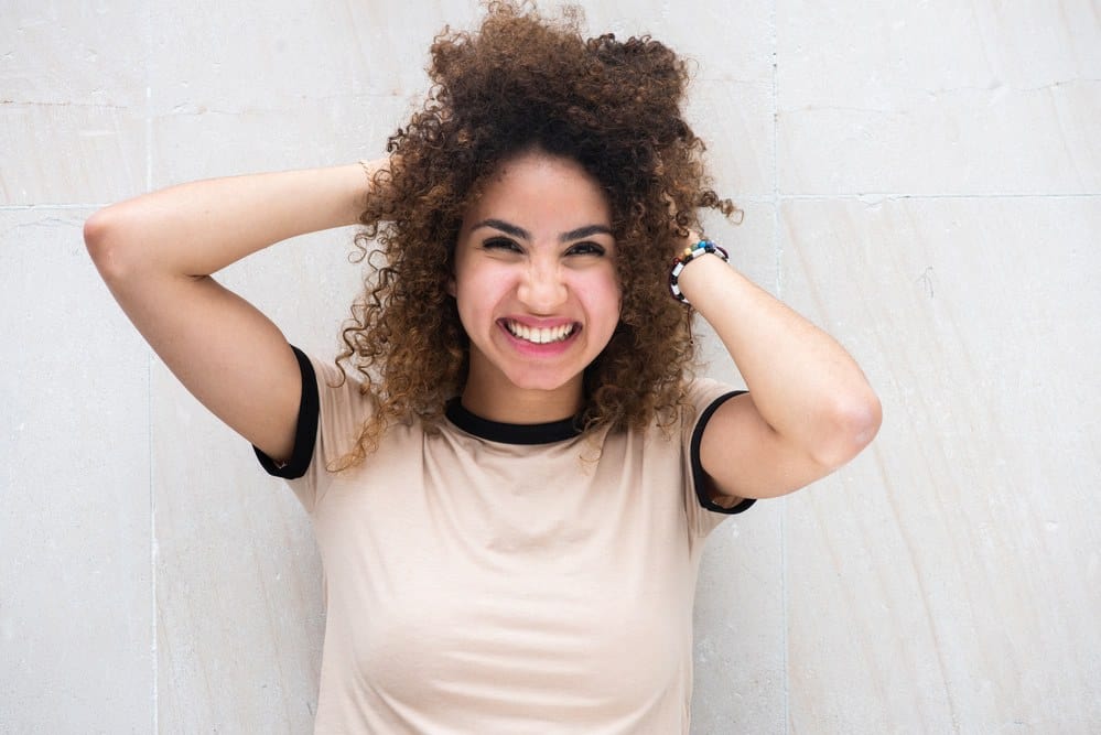 Black girl rubbing her hands through her hair after learning about the squish to condish method on Reddit.