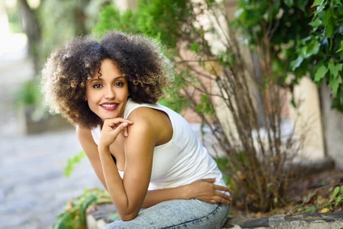 Young college student sitting in the park wearing a white t-shirt and blue jeans.