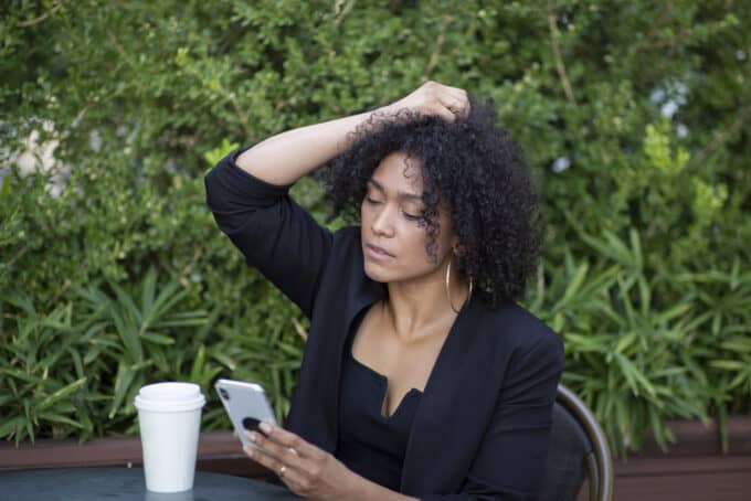 Cute black woman wearing a black dress holding her type 4A curly hair.