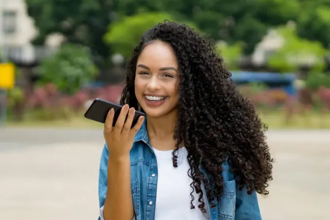 African American woman talking on a mobile phone with t3 curly hair wearing a blue jean shirt.