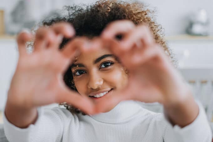 Black girl showing love to the camera with her hands.