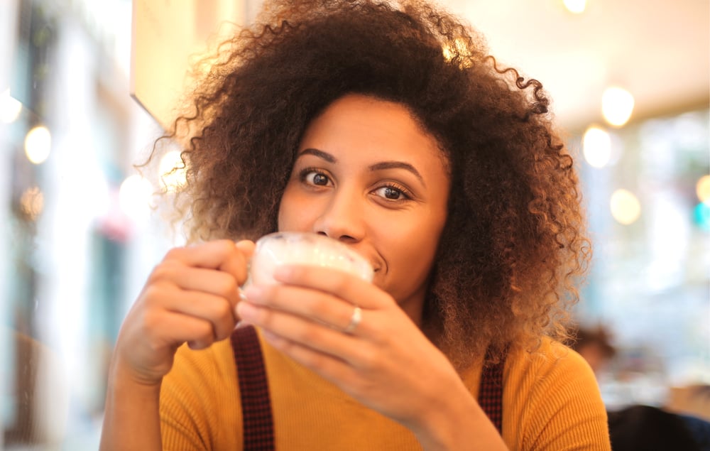 African American female with curly hair drinking coffee in Starbucks.