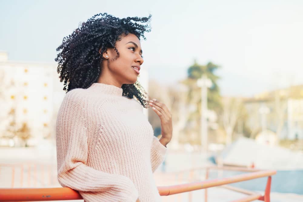 African American female with freshly washed long hair wearing a brown sweater and silver earrings.