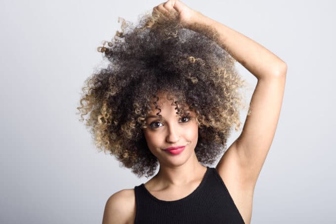 Beautiful black girl with a huge curly hairstyle looking directly into the camera with a huge small.