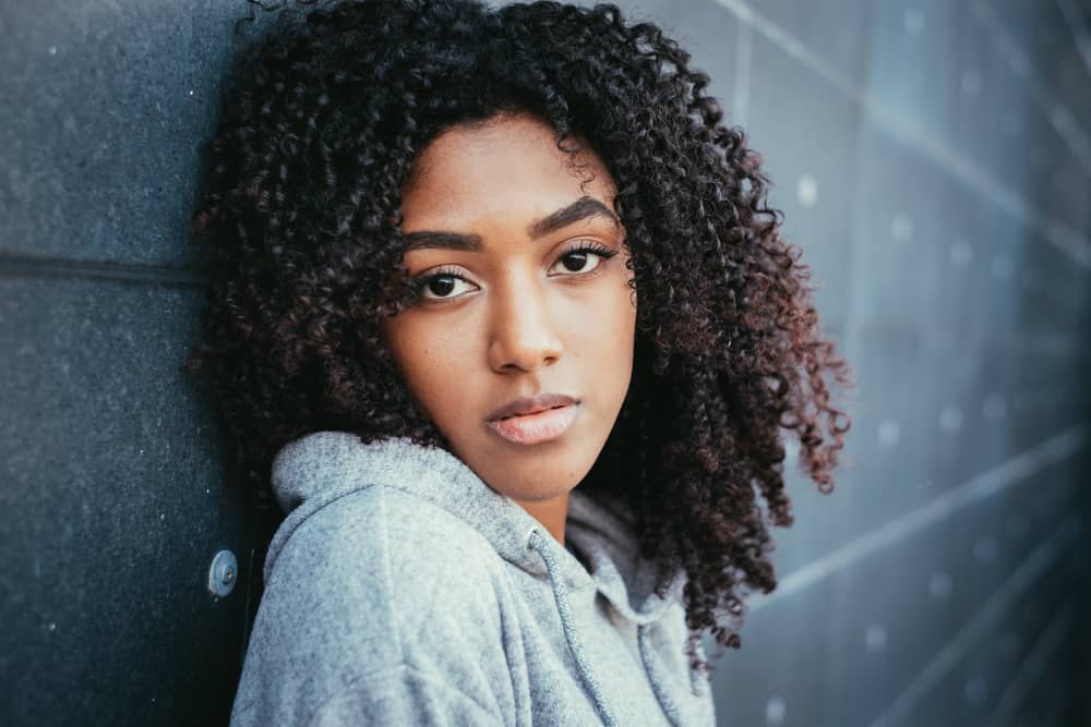 Cute African American female with perfect finger coils on 4A thick hair strands after using a hooded dryer.