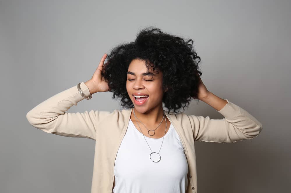 Beautiful African American female with curly hair with her eyes closed.