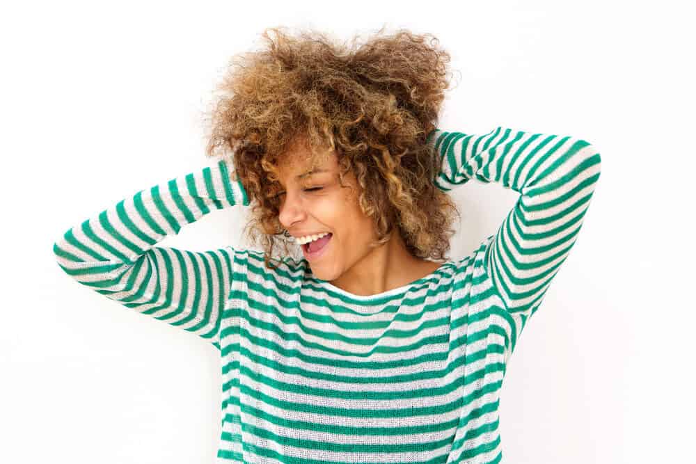 African American female with a wonderful smile rubbing her naturally curly hair