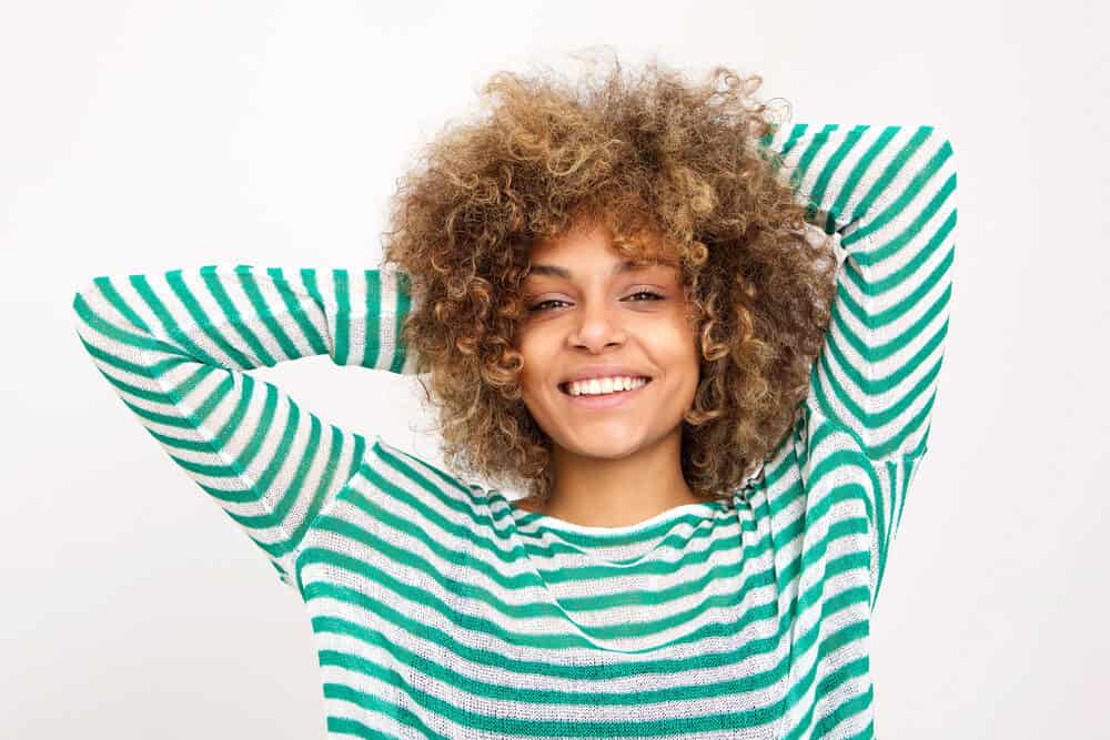 Black female with a green striped shirt feeling her hair after it's been washed with dish soap