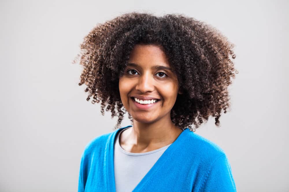 African American woman with type 4b curls wearing a blue sweater.