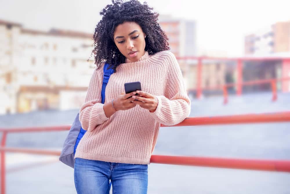 A black woman with short hair parted into several sections, wearing a brown sweater. Would look great in an advertisement.