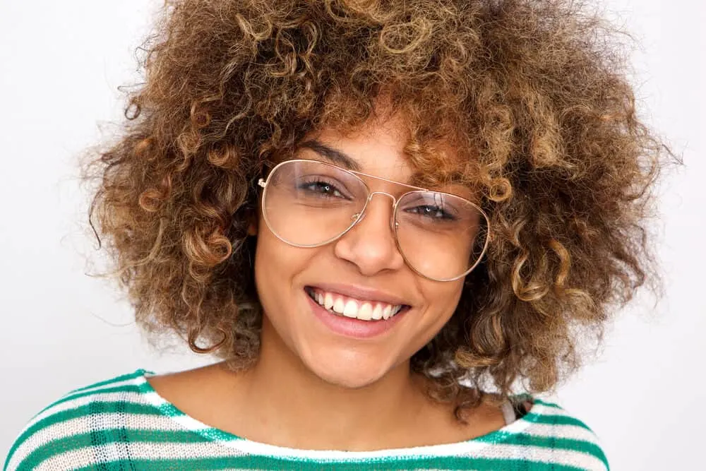 Black woman with a great smile with type 3 curly hair wearing glasses