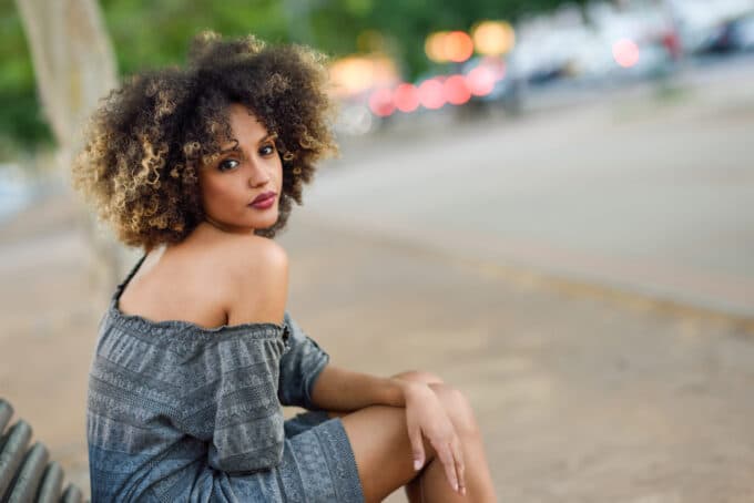 Black girl with a two-strand twist-out hairstyle wearing a black, gray, and blue patterned dress.