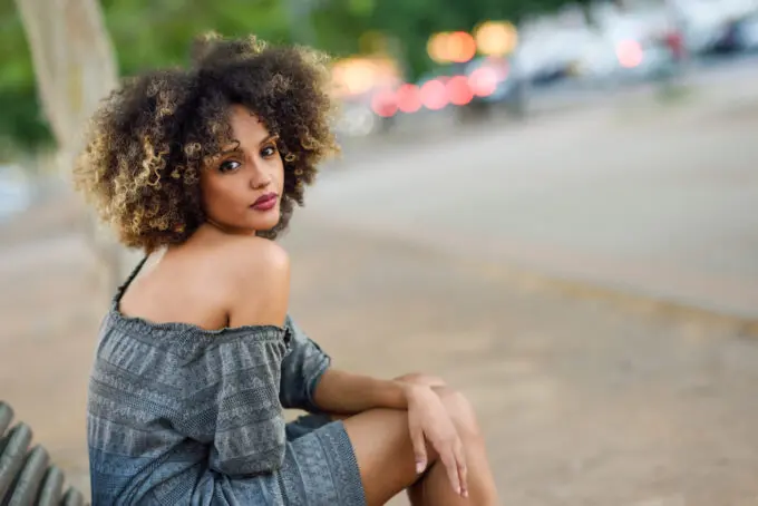 How To Dilute Hair Dye With Shampoo, Conditioner, Water, Pastel Colors, and More 2 Black girl with a two-strand twist-out hairstyle wearing a black, gray, and blue patterned dress.