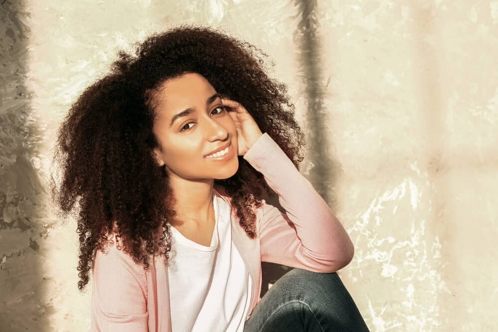 Beautiful African American female sitting on the ground near a grunge wall.