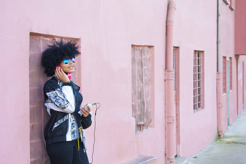 Cute female standing outside listening to music in an urban city.