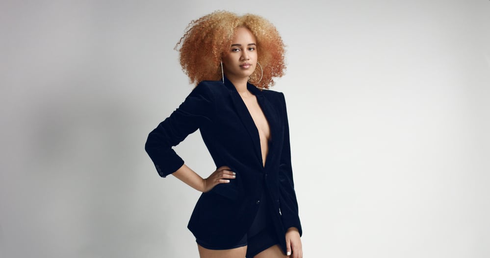 Black woman with round earrings, blonde hair, and white nail polish