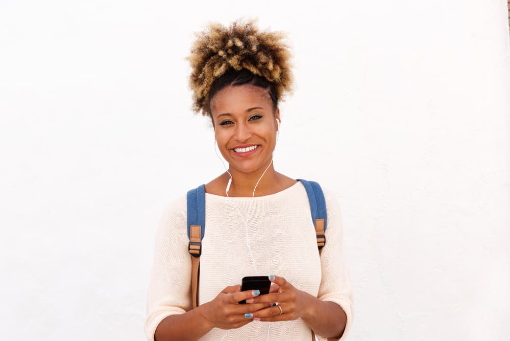 African American lady listening to the Curl Centric's podcast about natural hair care with earphones.