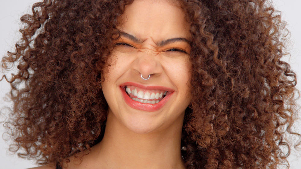Black woman with curly hair, a huge smile, and curly highlights.