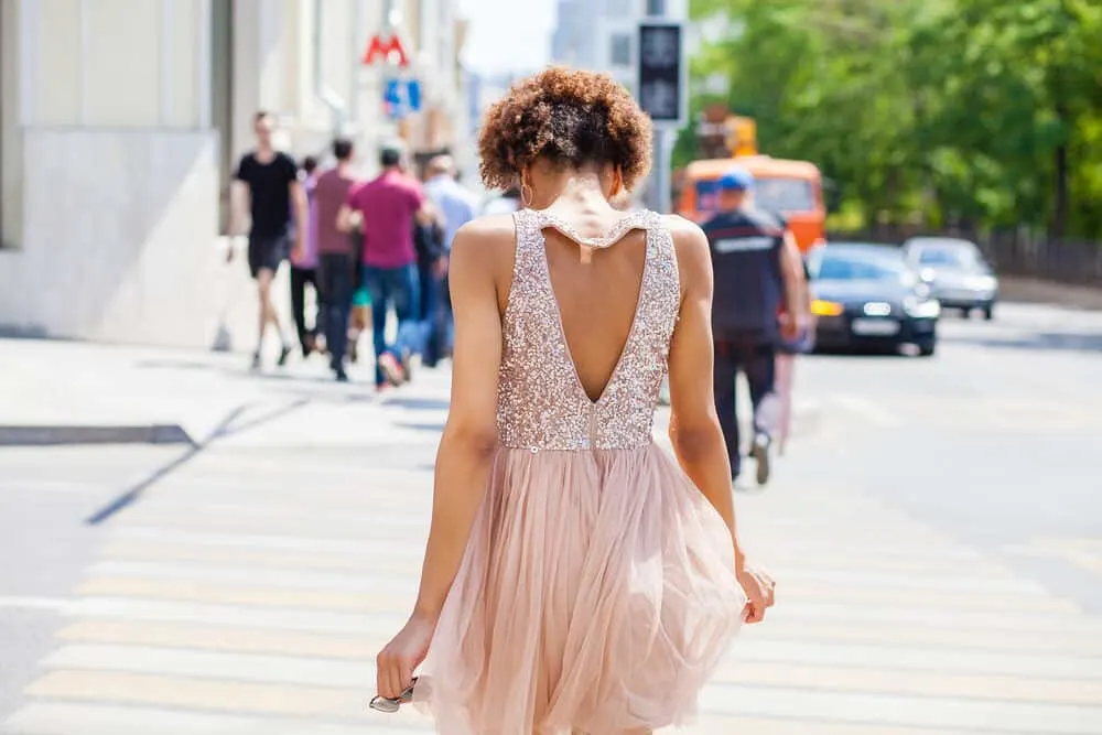 Skinny black girl with type 4 curls wearing a prom-style dress with sequins.